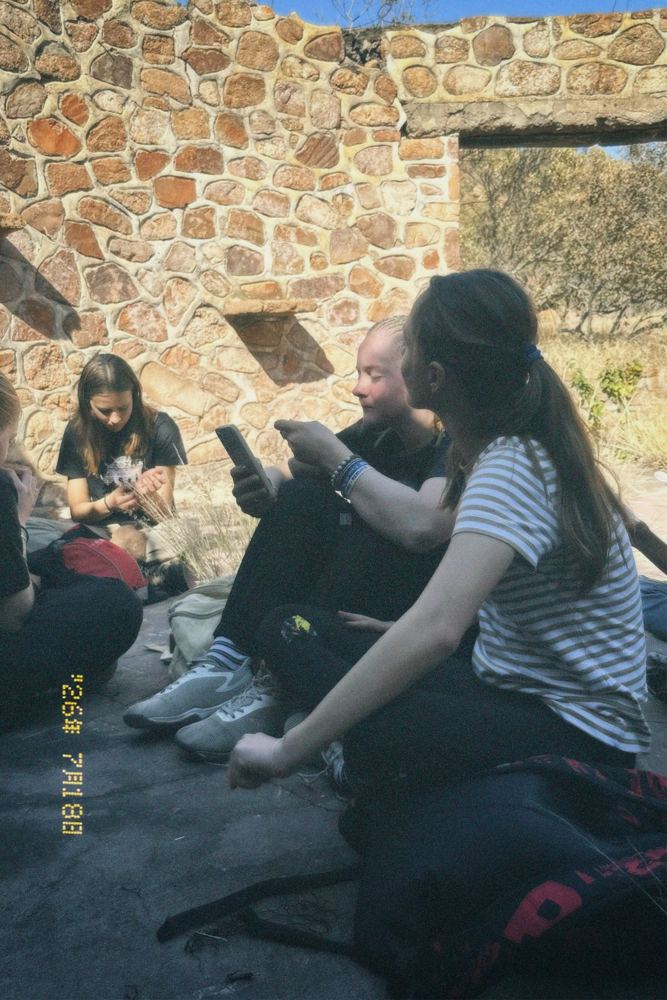 Girls sitting together in a stone ruin during a camp activity