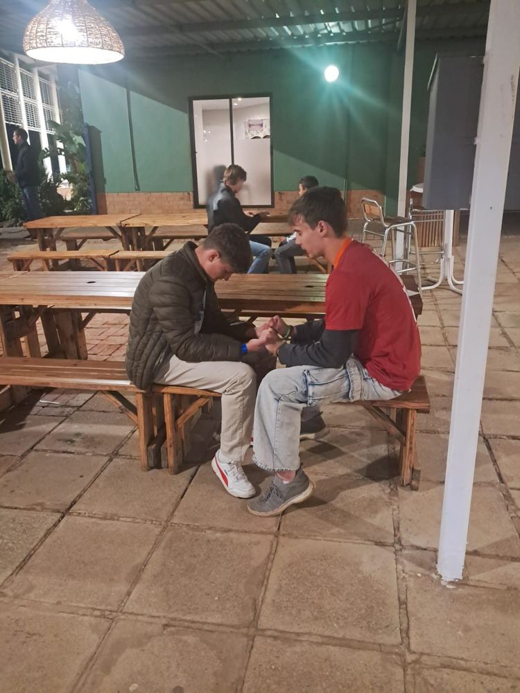 An adult supporter in a one-on-one conversation with a teenager at a picnic table